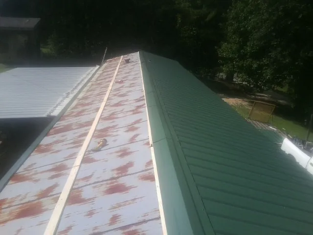 Old rusted panels beside newly installed green metal roofing — Wind Damage Roof Repair by Roofing Brothers in Long Valley