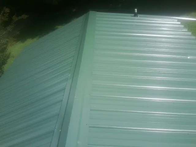 New green metal panels meeting at the ridge of a roof — Flat Roof Repair work by our crew in Long Valley