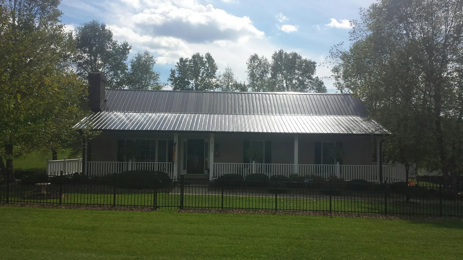 Gray metal roof on a brick ranch with a full width front porch — Gutter Guard Installation work by our crew in Long Valley