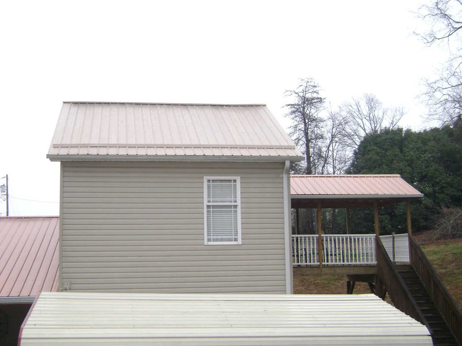 Tan metal roofs on a two story addition and attached porch, from a Roof Replacement job in Long Valley