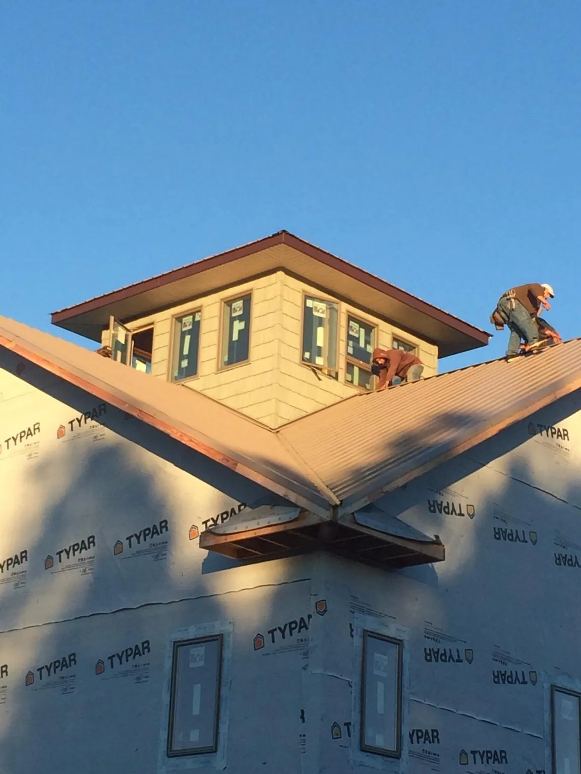 Roofers working around a rooftop cupola on a new metal roof at sunset — Roof Waterproofing in Long Valley by Roofing Brothers